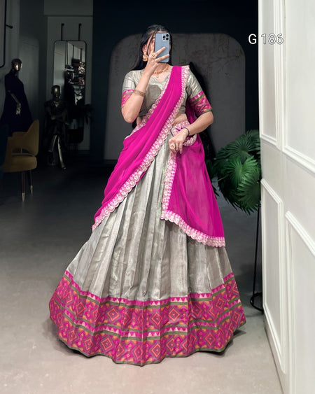 Person wearing a traditional outfit with a pink and gray design, standing indoors.