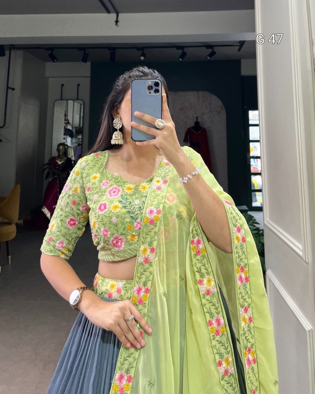 Person wearing a green floral saree with a matching blouse in an indoor setting.