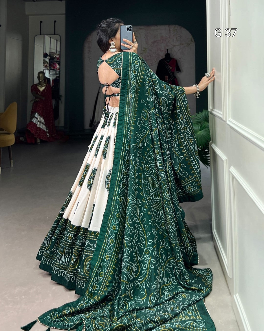Woman in a green and white saree with a patterned design, standing in a room.