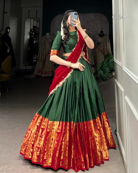 Person wearing a green and red traditional outfit with a patterned skirt, standing in a room.