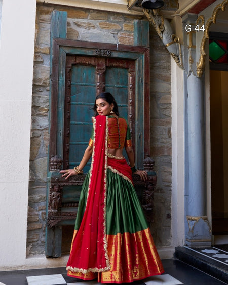 Woman in a traditional red and green saree standing in an ornate doorway.