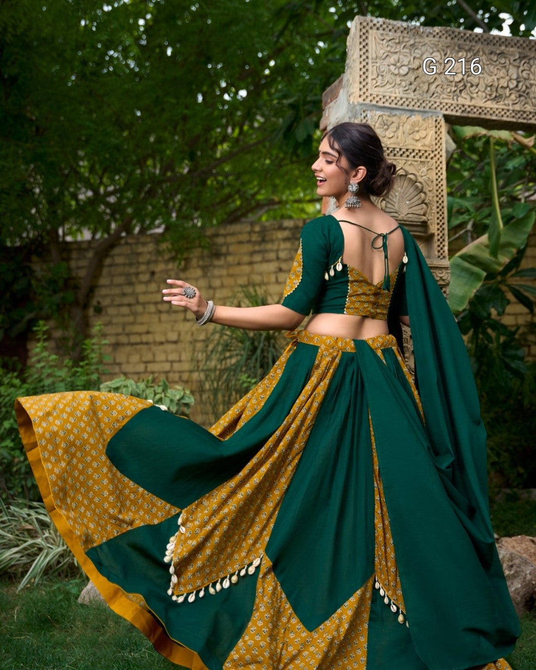 Woman in a green and yellow saree with a decorative background