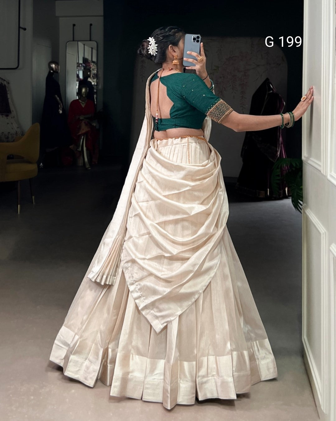 Person wearing a green blouse and white saree in a room with a mirror.