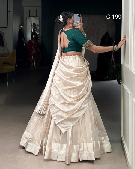 Person wearing a green blouse and white saree in a room with a mirror.
