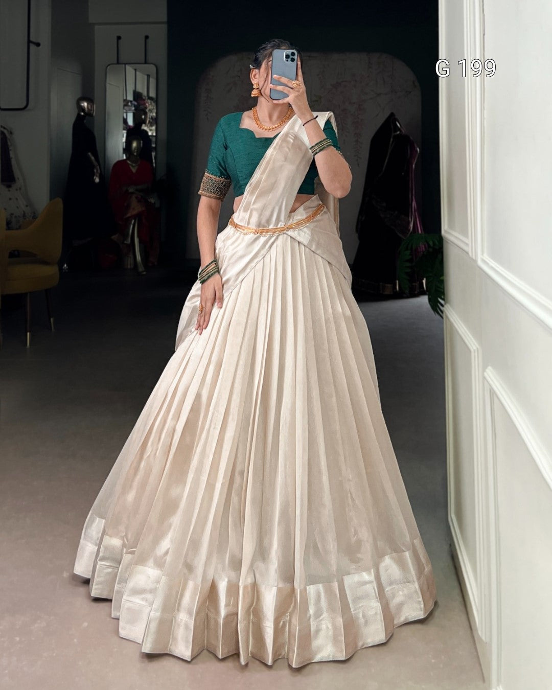 Woman wearing a white saree with a green blouse in a room.