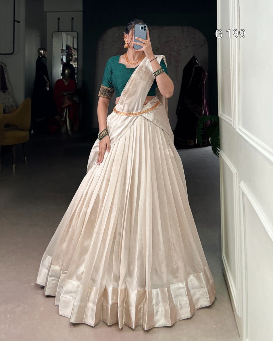 Woman wearing a white saree with a green blouse in a room.