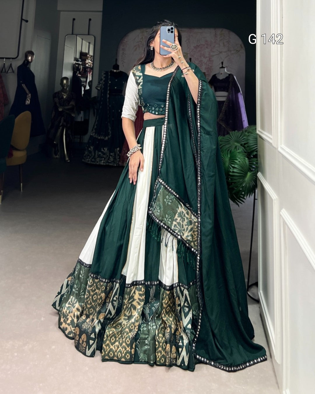 Person wearing a green and white traditional outfit with a patterned dupatta in a room.