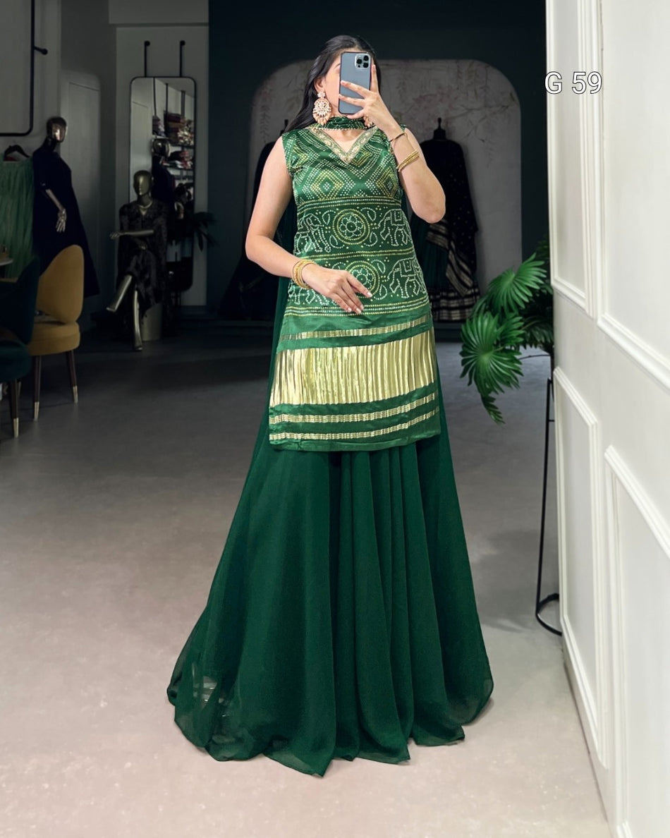 Person wearing a green traditional outfit with a patterned top and plain skirt, standing in a room.