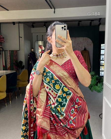 Person wearing a colorful saree taking a mirror selfie in an indoor setting.