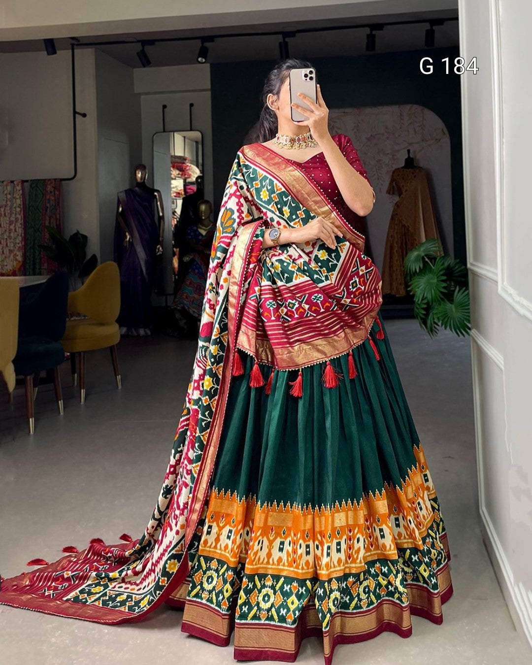 Person wearing a colorful traditional outfit in a room with furniture and decor.