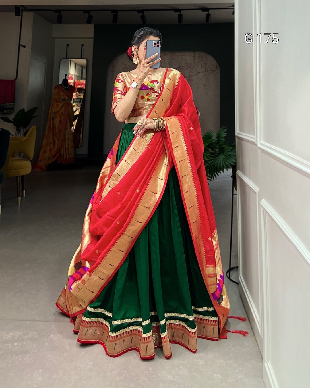 Woman wearing a traditional green and red saree with gold border indoors.