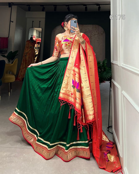 Person wearing a traditional green and red saree with a floral blouse, standing indoors.