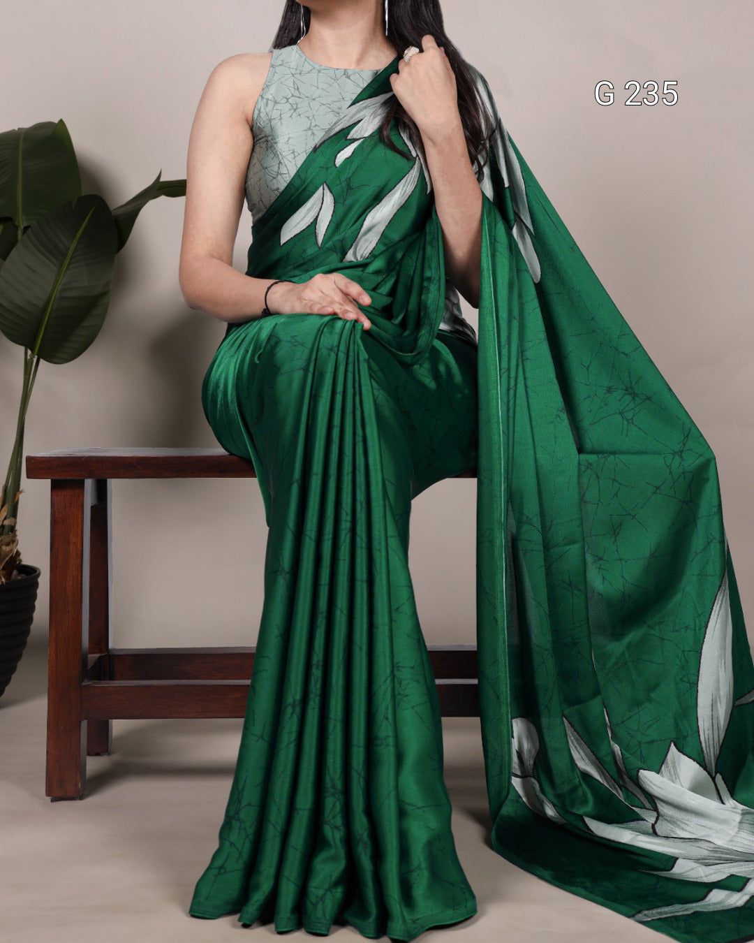 Woman holding a green saree with white patterns against a neutral background