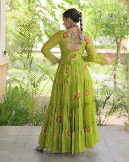 A woman wearing a bright lime green tiered Anarkali gown with red circular motifs, shown from the back in an outdoor garden setting.