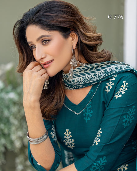 Woman wearing a teal embroidered outfit with a matching scarf, posing outdoors.