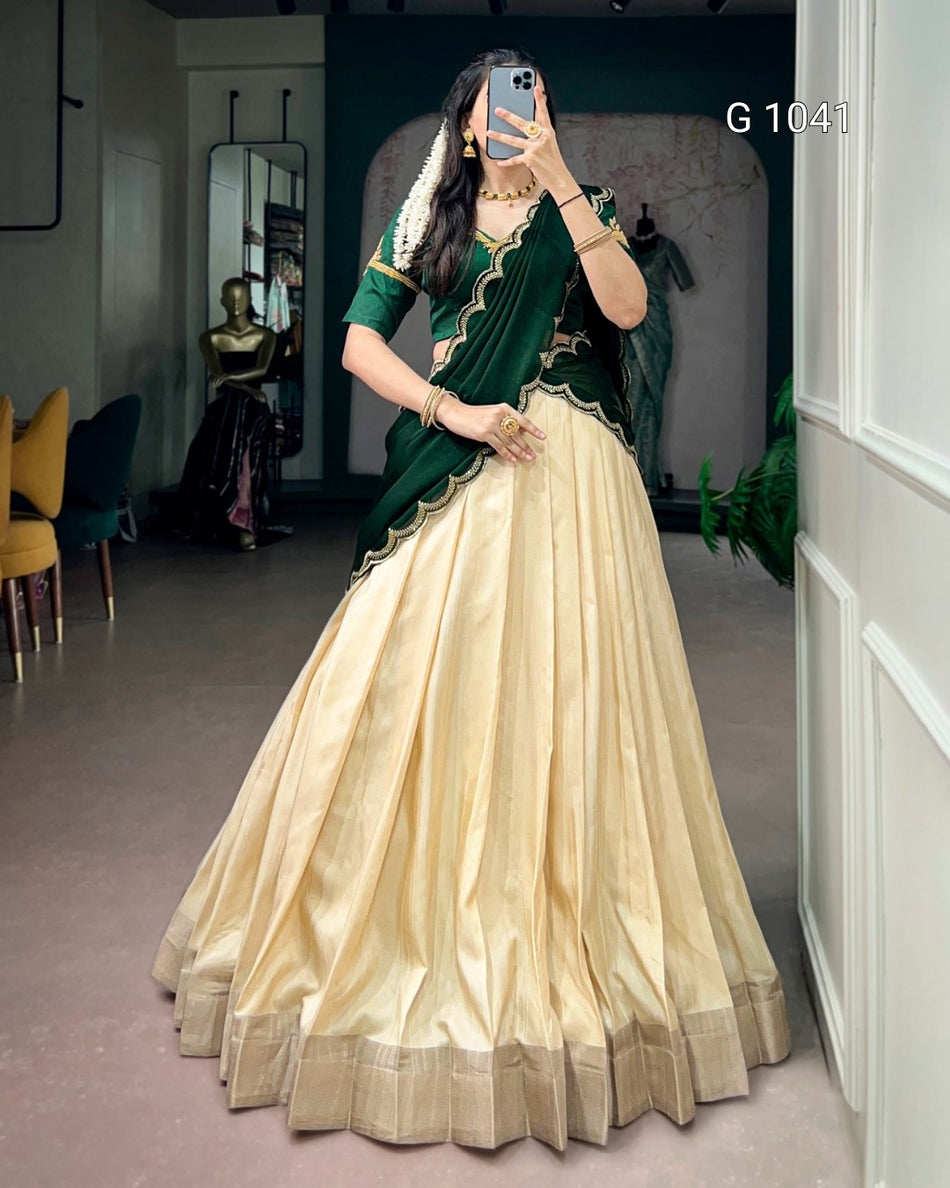 A woman takes a mirror selfie in a clothing boutique wearing a traditional Indian outfit consisting of a cream-colored flared skirt (lehenga), a dark green blouse with gold embroidery, and a matching dark green dupatta. The boutique interior is visible in the background, and the text 'G 1041' is printed on the right side.