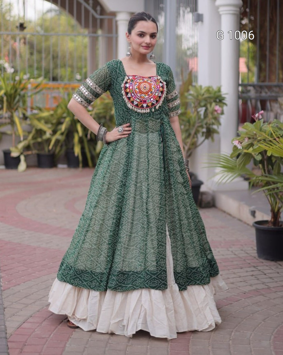 A woman models a green printed Anarkali gown with a heavily embellished mandarin-styled bodice and a layered cream ruffled underskirt, set against a residential outdoor backdrop with potted plants.