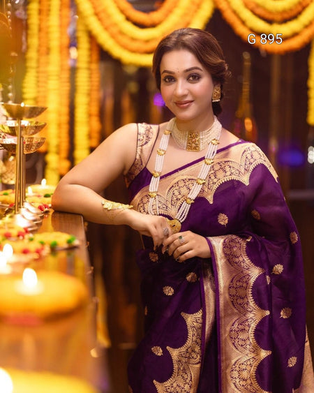 Woman in a purple saree with gold patterns in a decorated setting