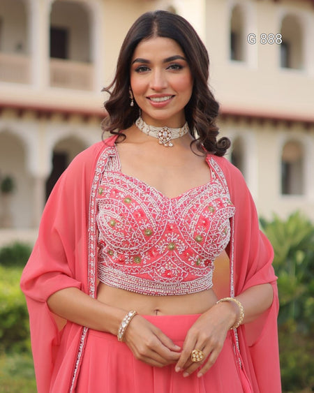 Woman in a pink traditional outfit with intricate designs, standing outdoors.