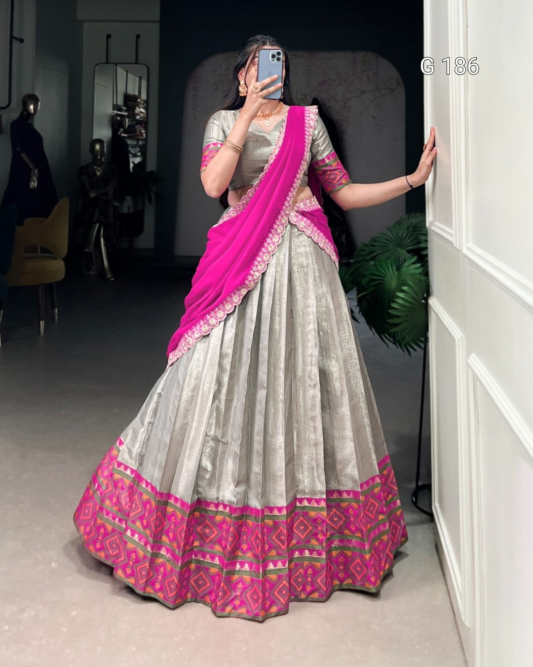 Person wearing a traditional outfit with a pink and white saree in a room.