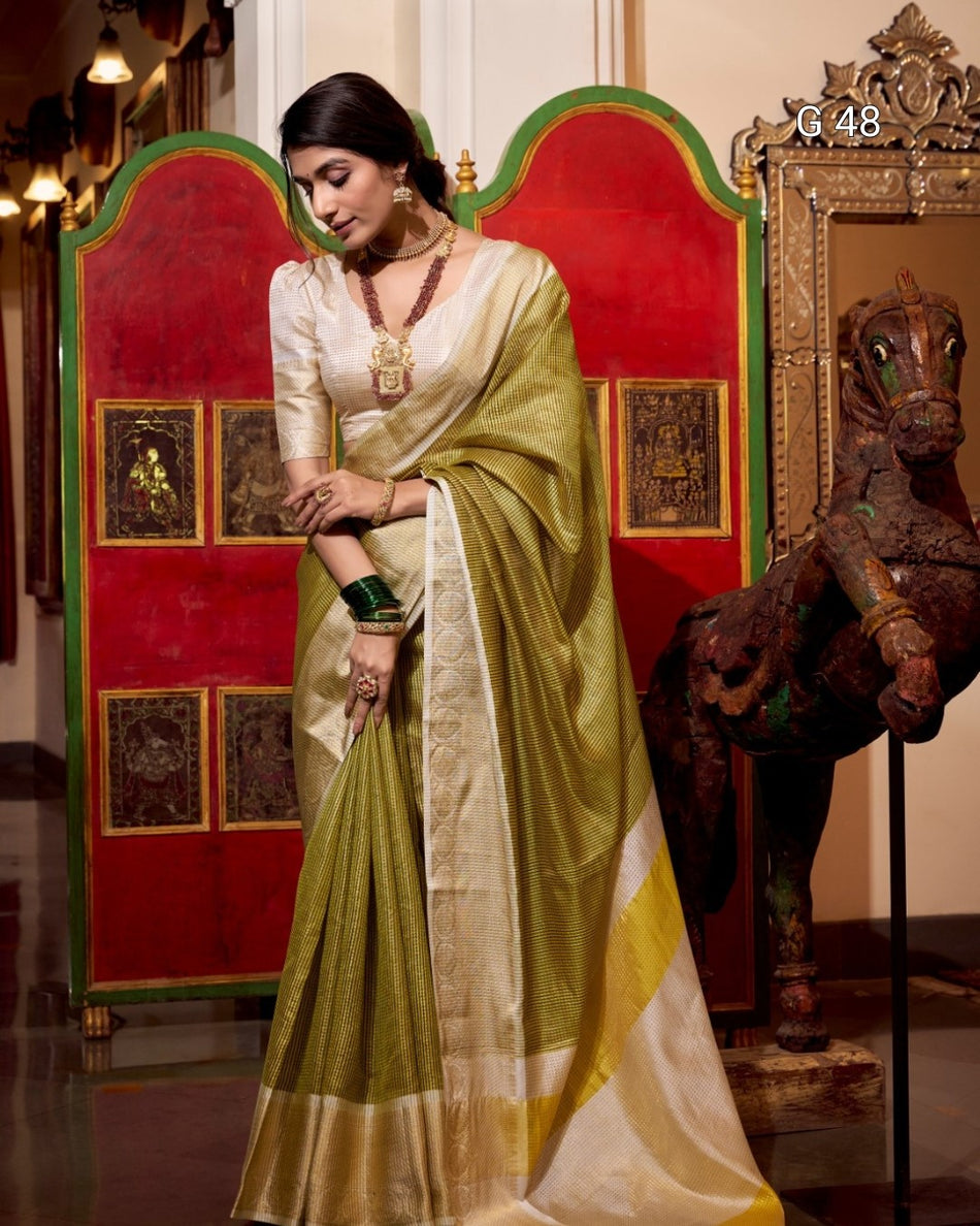 Woman in a green and white saree standing in front of a decorative screen and horse statue.