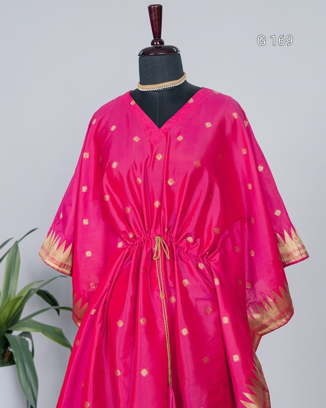 Pink dress with gold patterns on a mannequin against a gray background