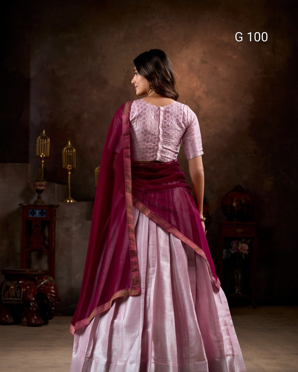 Woman wearing a traditional outfit with a pink blouse and maroon saree in a studio setting.