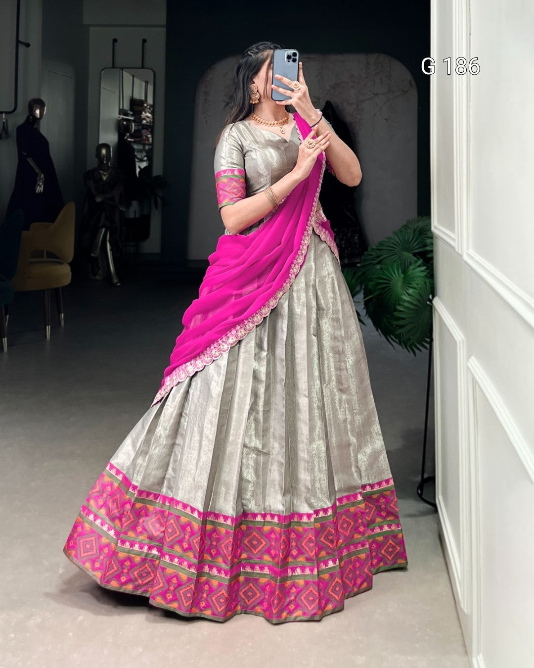 Woman taking a mirror selfie wearing a traditional outfit with a pink and gray color scheme.