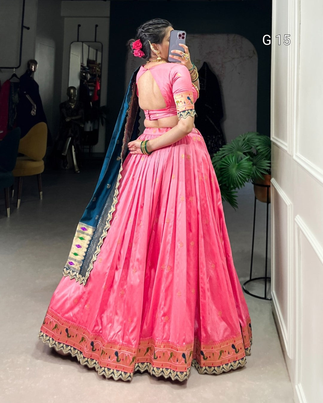 Person wearing a pink traditional outfit with a blue dupatta in an indoor setting.