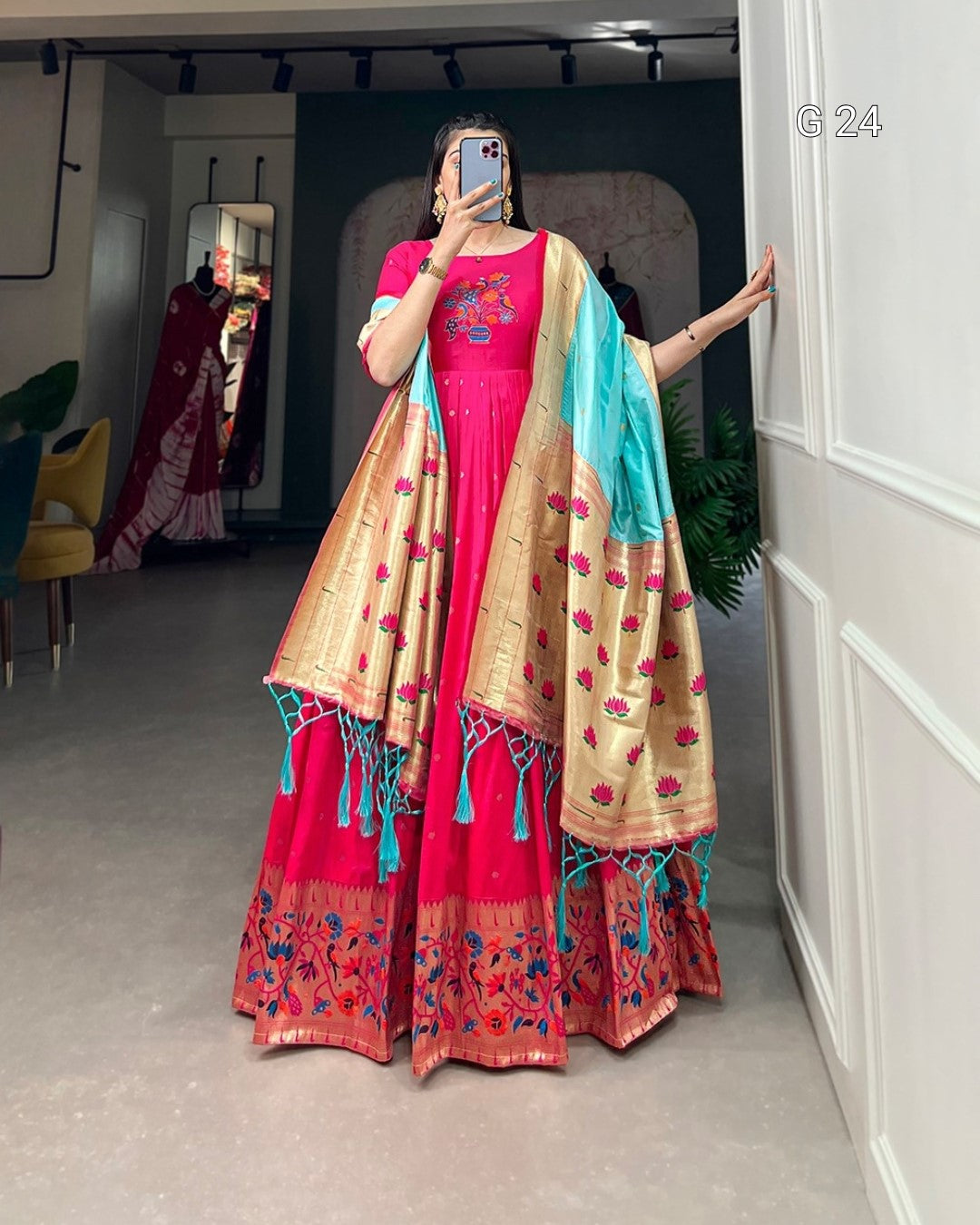 Person wearing a traditional outfit with a pink and gold saree in a room.