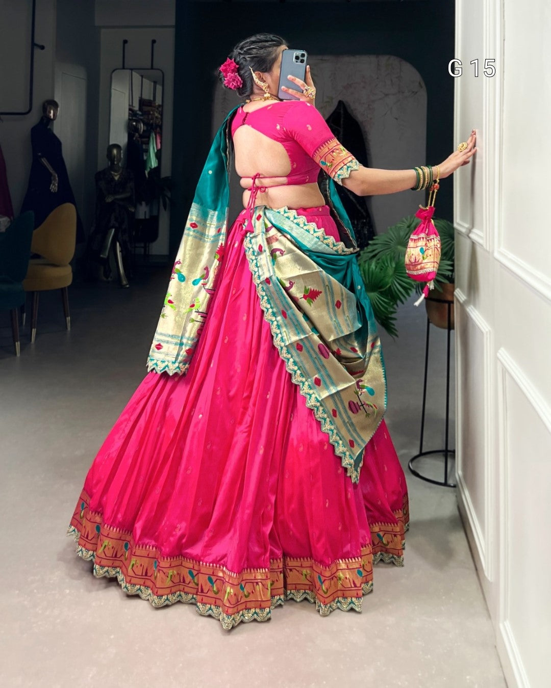 Woman in a bright pink traditional outfit with green and gold accents, standing in a room.