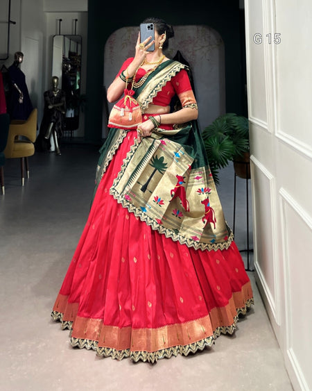 Woman in a red saree with green border taking a mirror selfie indoors.