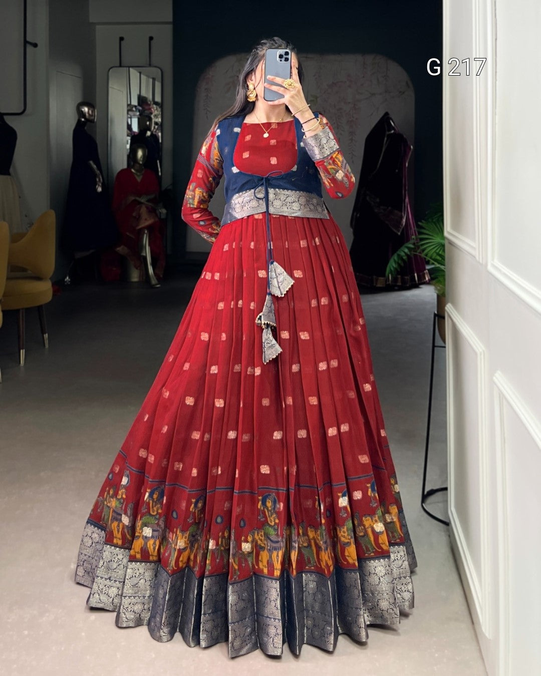 Person wearing a red and blue traditional outfit with intricate patterns in a room.