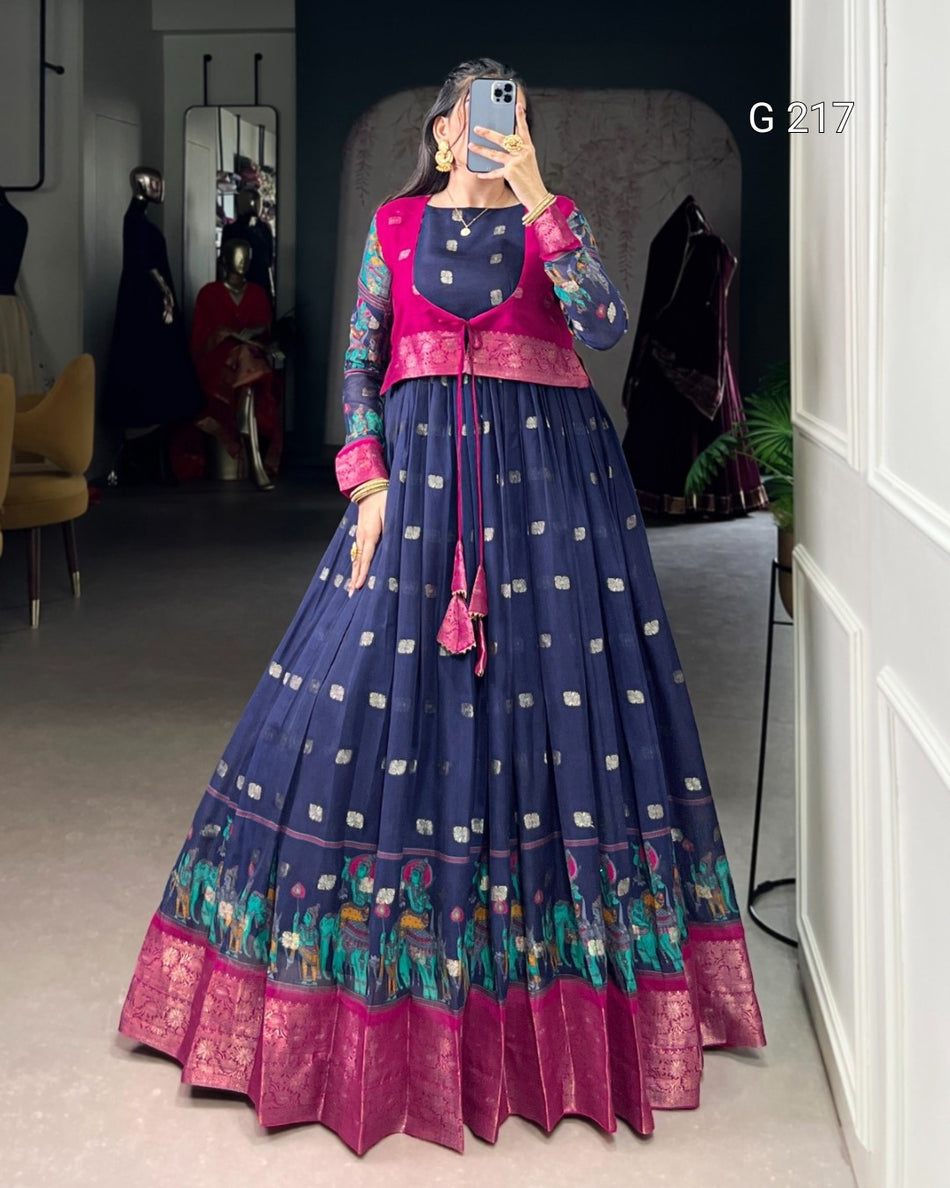Woman wearing a traditional blue and pink outfit with intricate patterns, standing in a room.