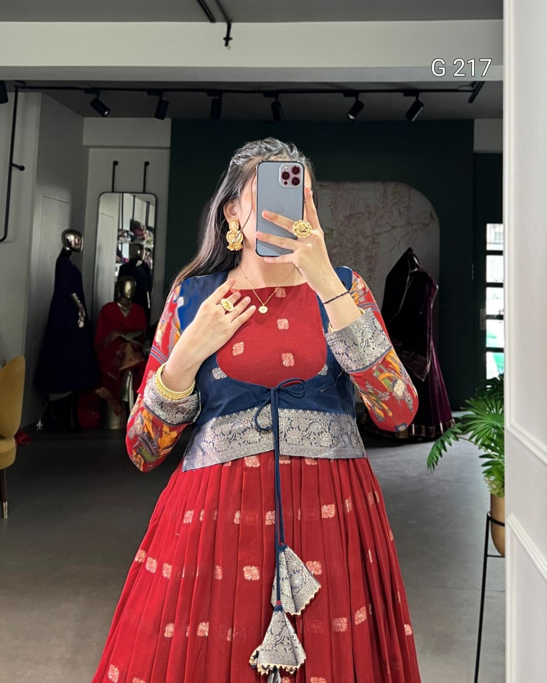 Person wearing a traditional outfit with a red and blue design, standing in a room.
