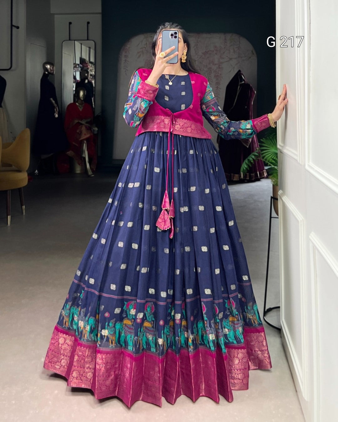 Woman taking a mirror selfie wearing a traditional outfit with a blue and pink design.