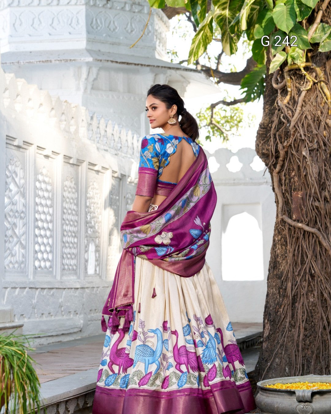 Woman in a colorful saree with a white architectural background