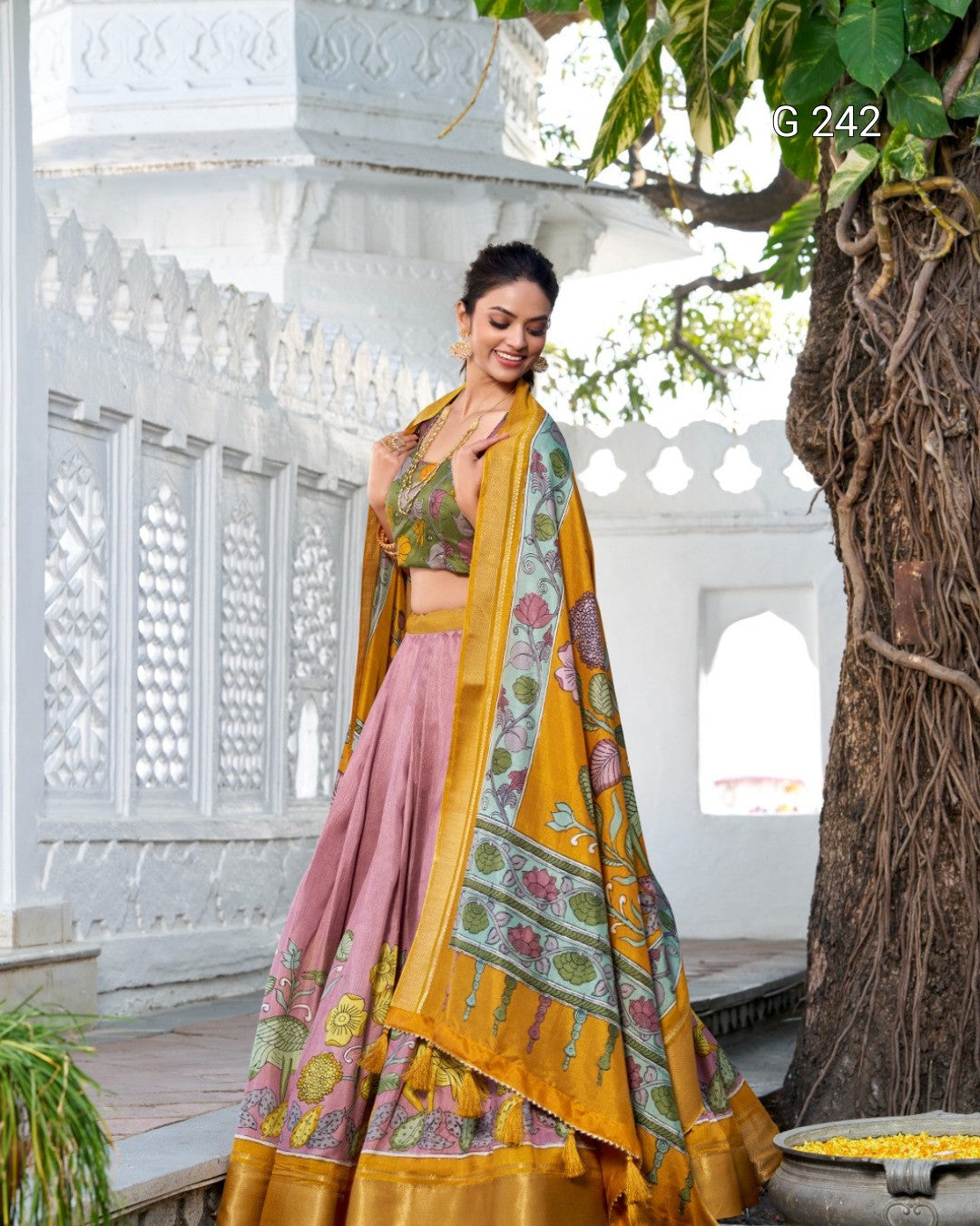 Woman in traditional Indian attire standing in a decorative outdoor setting.