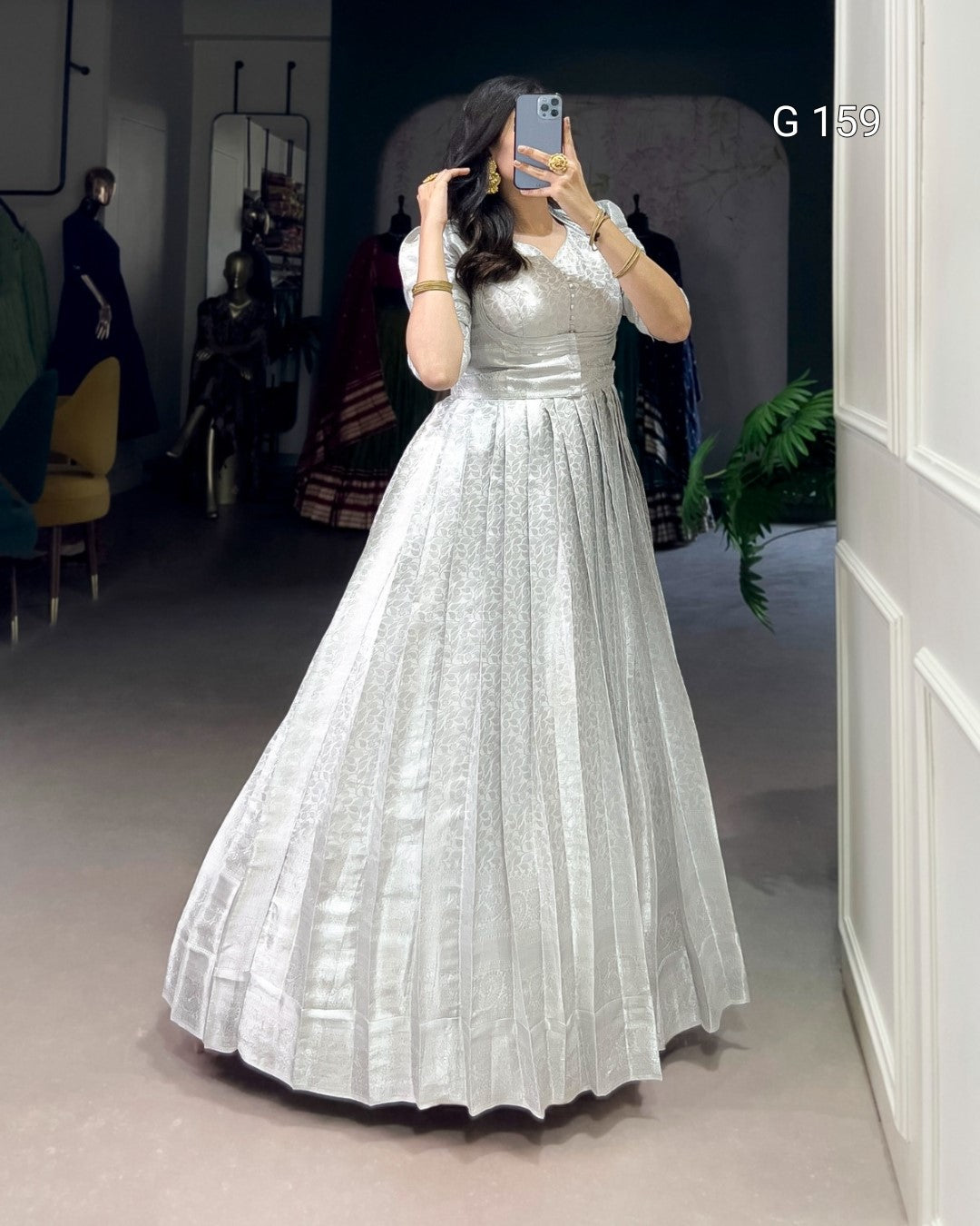 Person wearing a white dress taking a mirror selfie in an indoor setting.