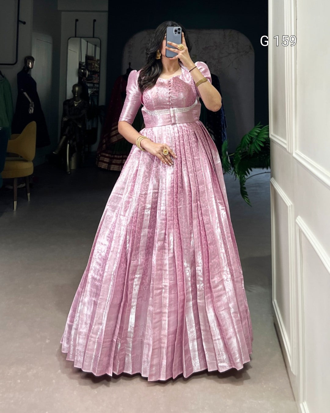 Woman wearing a pink dress taking a mirror selfie in an indoor setting.