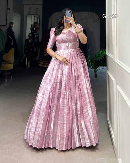 Woman wearing a pink dress taking a mirror selfie in an indoor setting.