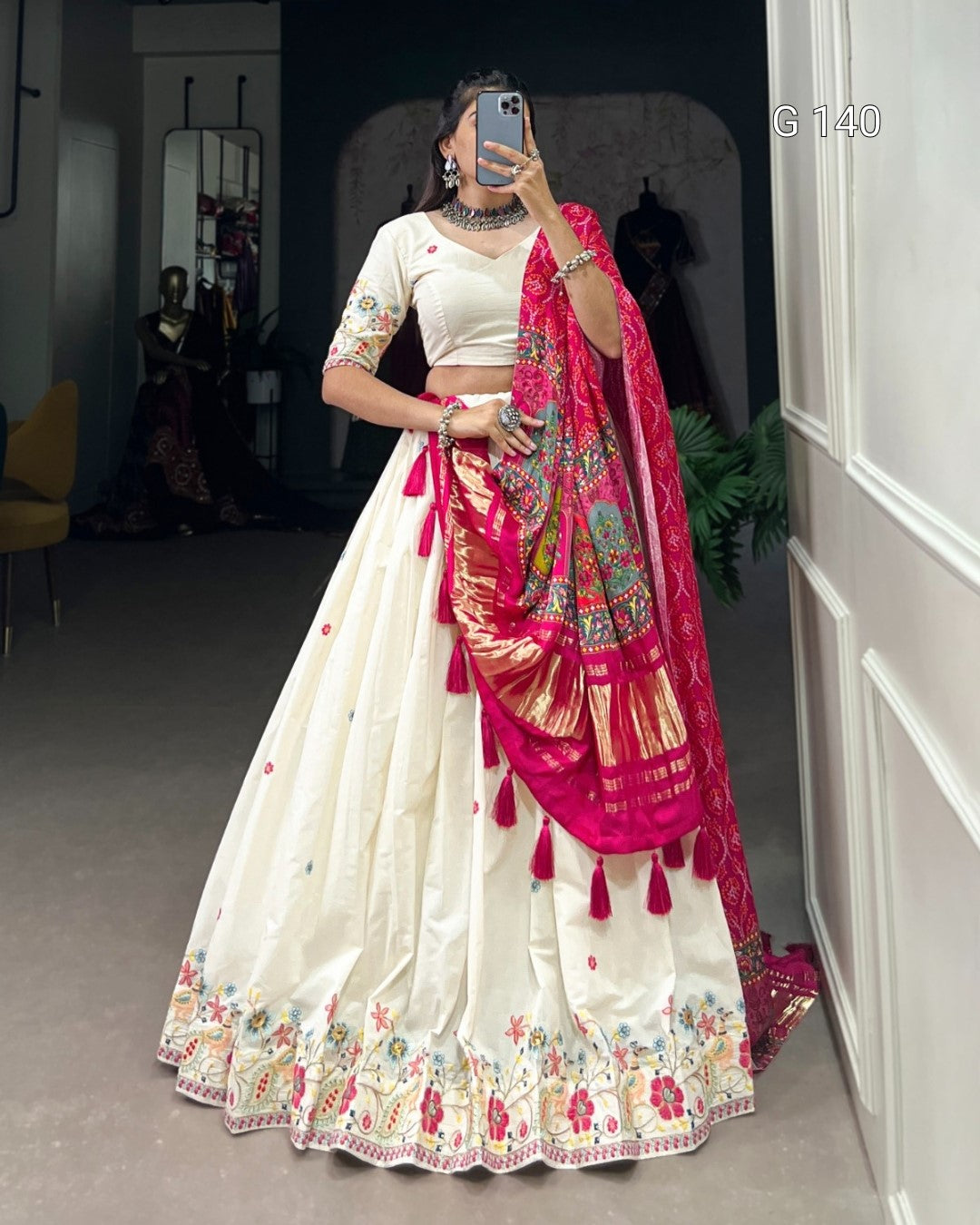 Woman in a traditional outfit with a white saree and pink dupatta in a room.