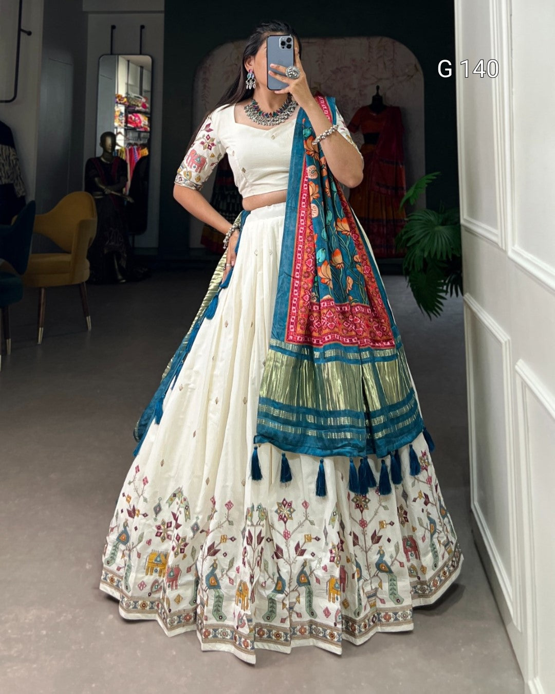 Woman in a traditional outfit with a colorful dupatta taking a mirror selfie.