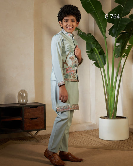 Child wearing a traditional outfit standing in a room with a plant and wooden cabinet.