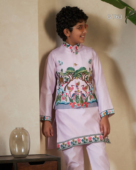 Child wearing a light pink embroidered traditional outfit against a beige wall.