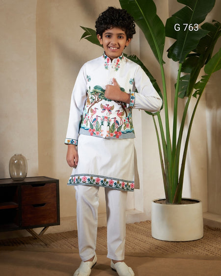 Young boy in traditional outfit standing indoors with a plant in the background
