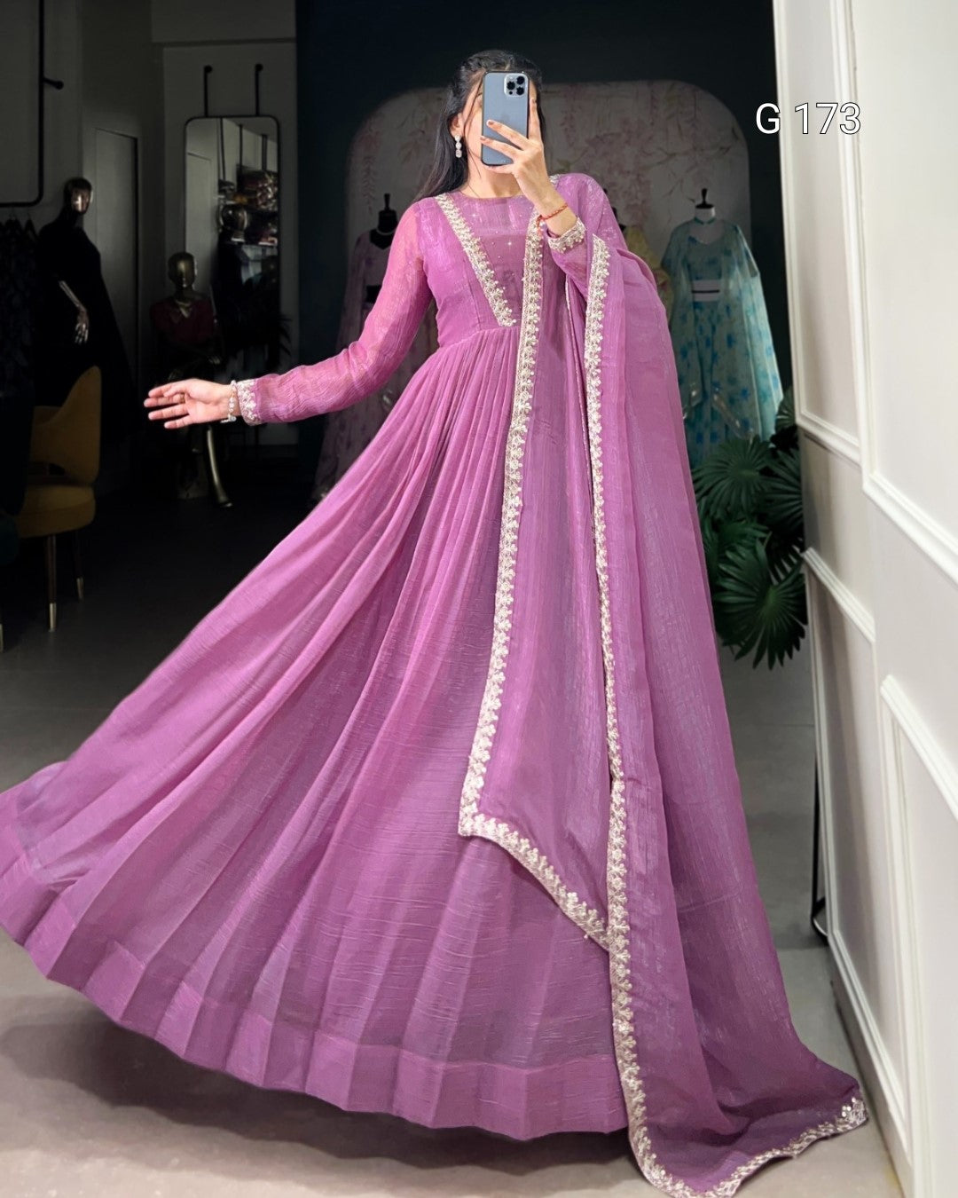 Person wearing a long purple dress with gold trim in a room.