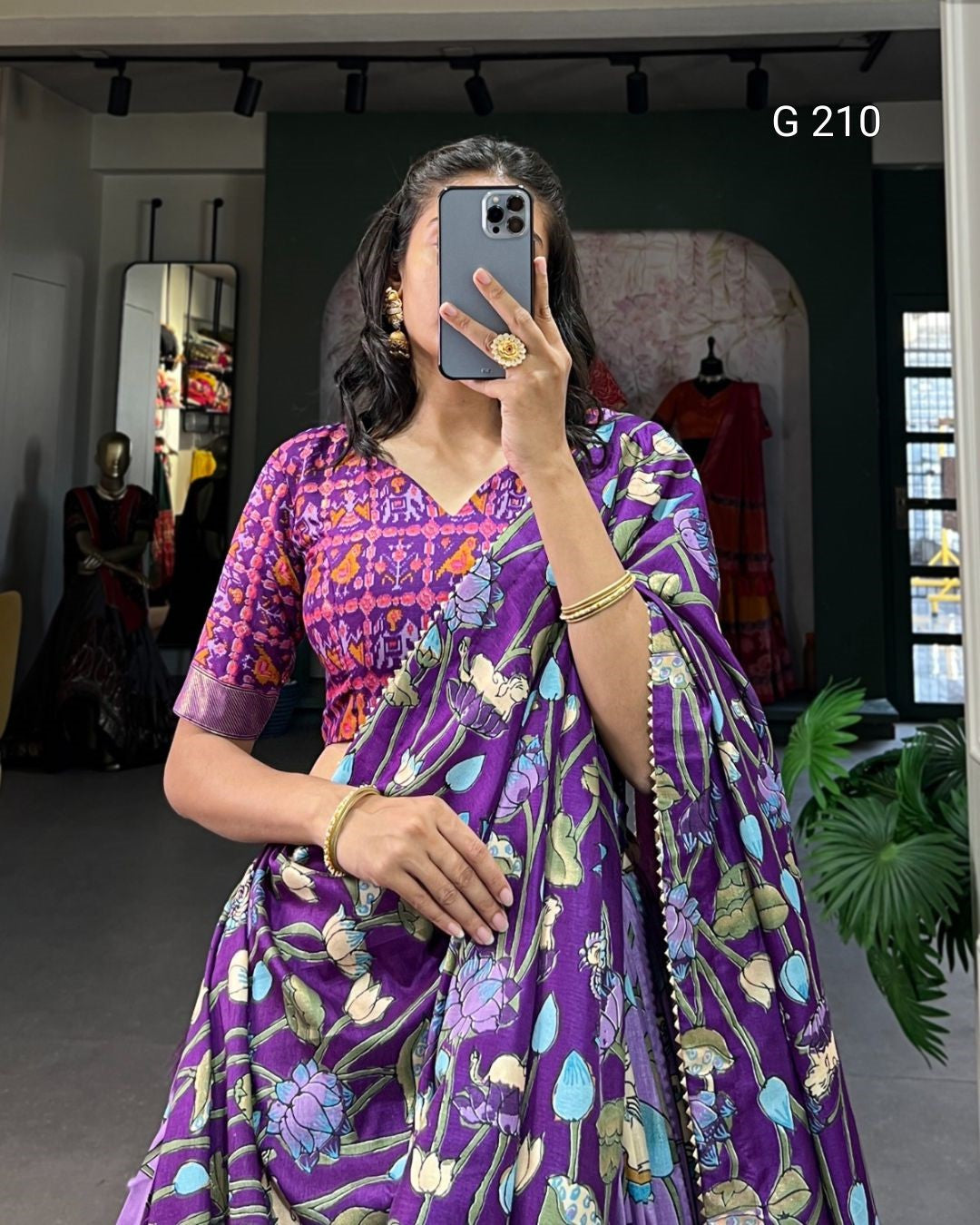 Person wearing a purple saree with floral patterns in an indoor setting.