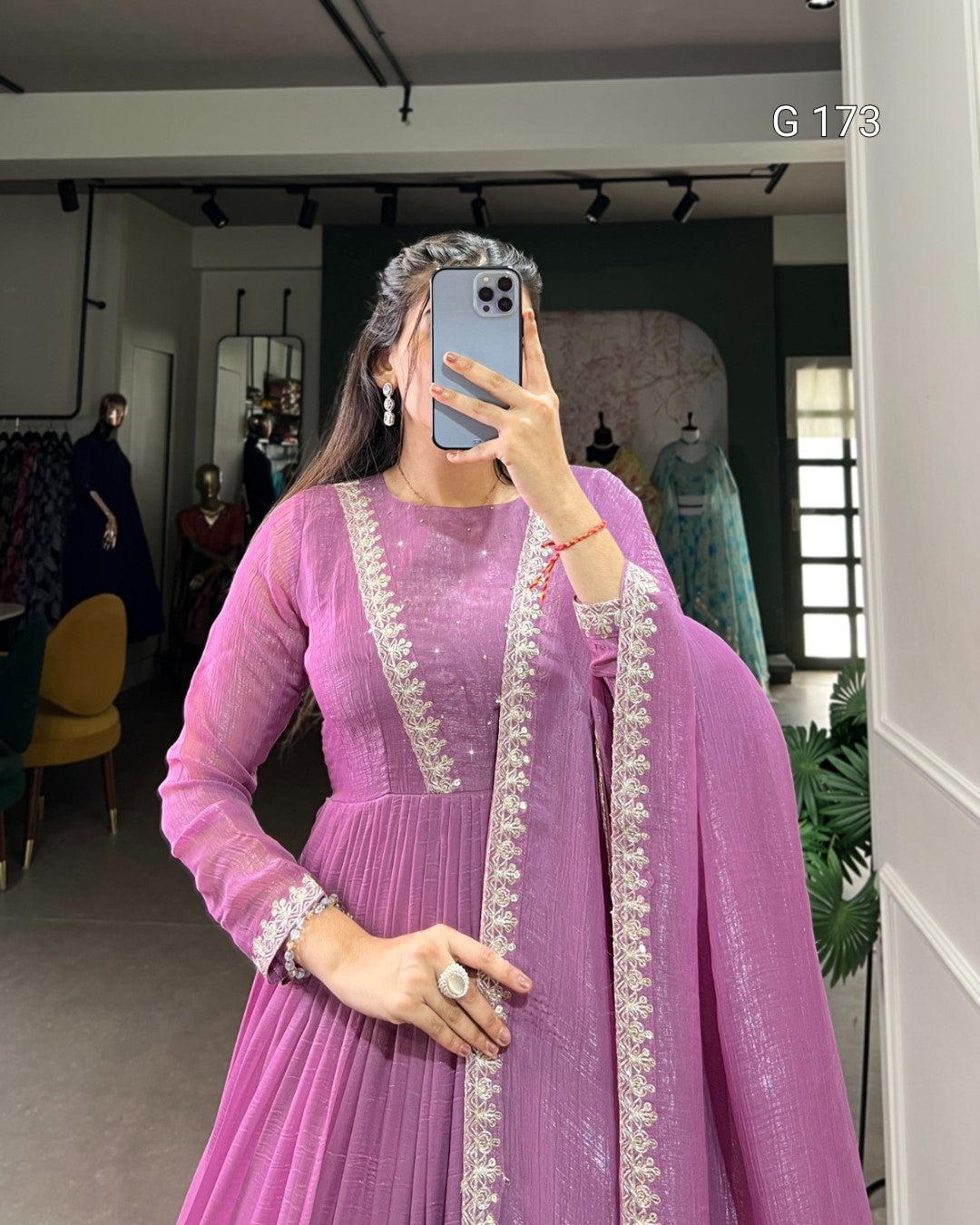 Person wearing a pink traditional outfit with white embroidery in a store setting.