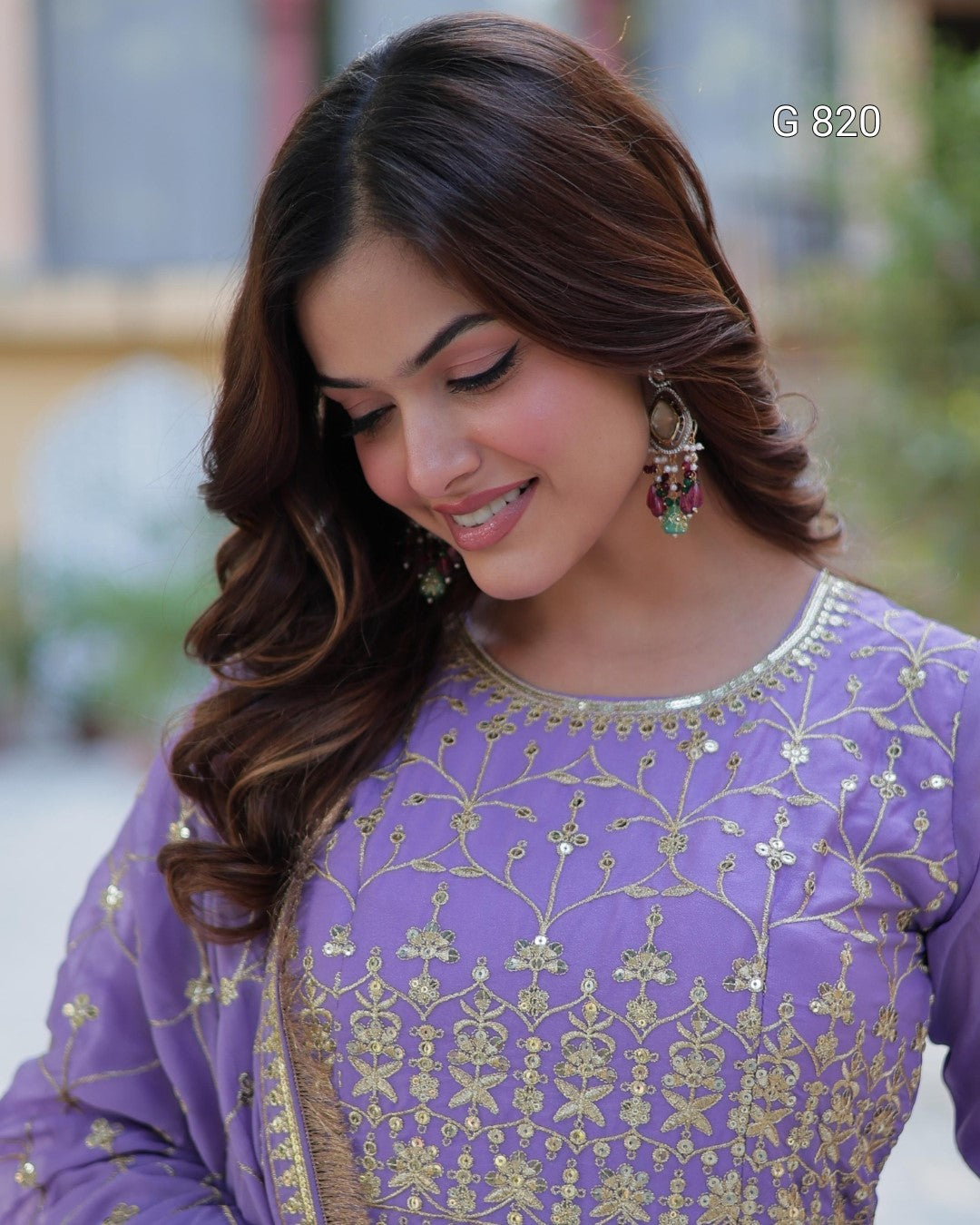 Woman wearing a purple embroidered outfit with a blurred outdoor background